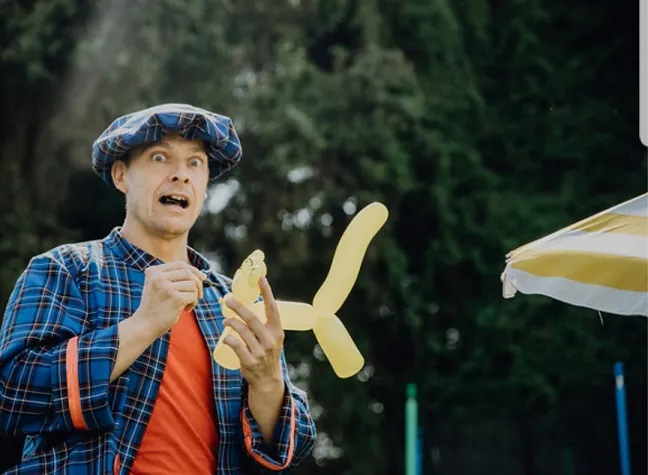 Le clown LIAR sculptant des ballons : un chien en ballon jaune prend forme